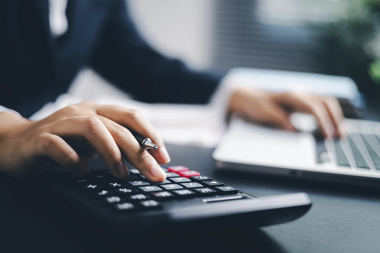 Profissional de contabilidade utilizando calculadora em ambiente de escritório, representando a análise do cálculo de desconto PJ.
